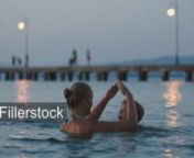 Mother and son playing in the sea in the evening. Woman making house from hands and boy getting there kissing mom. Summer vacation - License this clip: https://fillerstock.com/video/2646